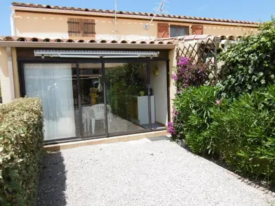 a sliding glass door with a chair in a garden at Charmante villa T2 mezzanine avec cour, jardin, véranda, barbecue et parking privé, proche plage et commerces - FR-1-797-2 in Port-la-Nouvelle