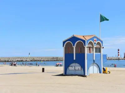 a small blue building on a beach with people in the water at Bel appartement T2 climatisé avec piscine et parking à 250m de la plage - FR-1-797-9 in Port-la-Nouvelle