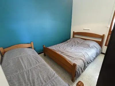 a bedroom with two beds and a blue wall at T2 climatisé en front de mer avec parking - FR-1-797-13 in Port-la-Nouvelle