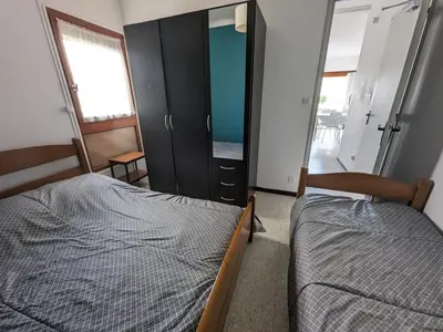 a bedroom with two beds and a dresser and a mirror at T2 climatisé en front de mer avec parking - FR-1-797-13 in Port-la-Nouvelle