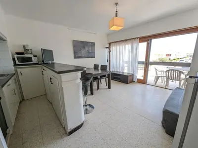 a kitchen and living room with a table and a microwave at T2 face mer, climatisé, parking privé, 4 pers - FR-1-797-11 in Port-la-Nouvelle