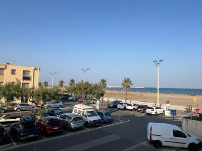 a parking lot with cars parked next to the beach at T2 face mer, climatisé, parking privé, 4 pers - FR-1-797-11 in Port-la-Nouvelle