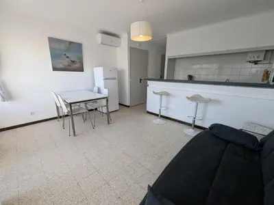 a living room with a table and a kitchen at Agréable T2 pour 5 pers, 1er étage, climatisé, parking sécurisé - FR-1-797-6 in Port-la-Nouvelle