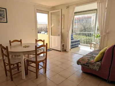 a living room with a table and chairs and a balcony at Appartement T2 lumineux 40m2, 4 personnes, 150m de la plage, bien équipé et proche loisirs - FR-1-797-18 in Port-la-Nouvelle