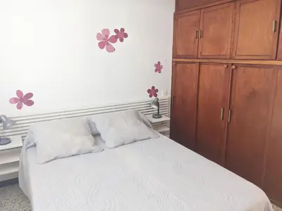 a bedroom with a white bed and a wooden cabinet at Charmant T3 rénové à 60m de la plage avec terrasse, jardin et parking clos - FR-1-797-28 in Port-la-Nouvelle