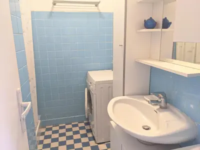 a bathroom with a sink and a toilet and blue tiles at Charmant T3 rénové à 60m de la plage avec terrasse, jardin et parking clos - FR-1-797-28 in Port-la-Nouvelle