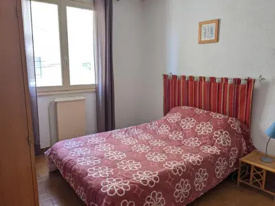 a bedroom with a bed with a red comforter and a window at Appartement T4 proche plage et commerces, 80m2, 6 pers, lave-linge, TV - FR-1-797-23 in Port-la-Nouvelle