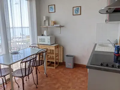 a kitchen with a table and chairs and a microwave at Appartement T4 proche plage et commerces, 80m2, 6 pers, lave-linge, TV - FR-1-797-23 in Port-la-Nouvelle