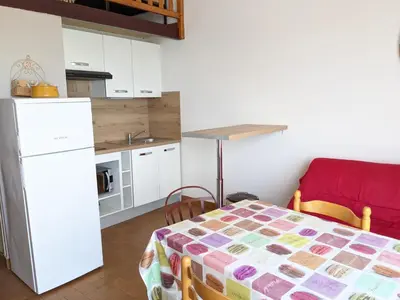 a small kitchen with a table and a refrigerator at Appartement T2 mezzanine 4/5 pers à 250m de la plage, balcon, vue panoramique - FR-1-797-26 in Port-la-Nouvelle