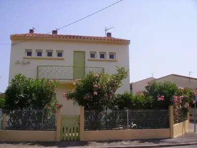 a white house with a fence and pink flowers at Agréable T2, 4 pers, plain-pied ouvert sur terrasse, jardin clos, parking privé, proche plage et commerces - FR-1-797-24 in Port-la-Nouvelle