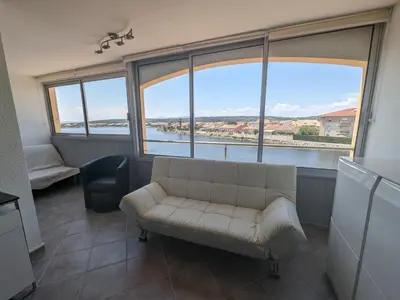 a living room with a couch and large windows at Grand T2 Climatisé 36m² avec Parking à 450m de la Plage - 4 Pers - FR-1-797-34 in Port-la-Nouvelle