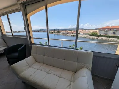 a living room with a white couch and a large window at Grand T2 Climatisé 36m² avec Parking à 450m de la Plage - 4 Pers - FR-1-797-34 in Port-la-Nouvelle