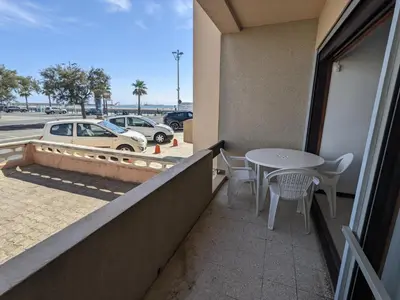 a balcony with a table and chairs and a parking lot at T2 Climatisé, 5 pers, Parking Protégé, Front de mer - FR-1-797-38 in Port-la-Nouvelle