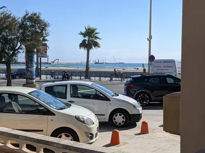 three cars parked in a parking lot next to the beach at T2 Climatisé, 5 pers, Parking Protégé, Front de mer - FR-1-797-38 in Port-la-Nouvelle