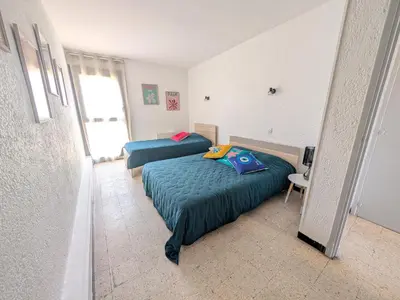 a bedroom with two beds and a table and a chair at Appartement T2 Front de Mer avec Balcon et Parking – Confort et Activités à Proximité - FR-1-797-37 in Port-la-Nouvelle