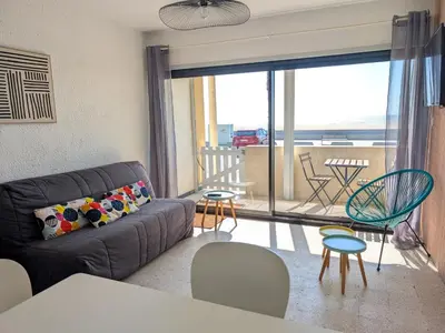 a living room with a couch and a balcony at Appartement T2 Front de Mer avec Balcon et Parking – Confort et Activités à Proximité - FR-1-797-37 in Port-la-Nouvelle