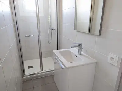 a white bathroom with a shower and a sink at Port-la-Nouvelle : T2 proche plage, terrasse, parking, clim, BBQ, lave-linge, 4 pers, classé 2* - FR-1-797-17 in Port-la-Nouvelle