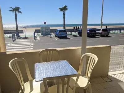 a table and chairs on a balcony with a view of the beach at T2 en bord de mer pour 4 pers, RDC avec Parking - FR-1-797-39 in Port-la-Nouvelle