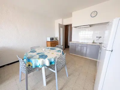 a kitchen with a table and chairs and a refrigerator at T2 en bord de mer pour 4 pers, RDC avec Parking - FR-1-797-39 in Port-la-Nouvelle