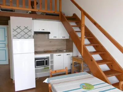 a kitchen with a staircase leading up to a loft at T2 Mezzanine à 250m de la plage pour 4/5 pers avec Parking et TV - FR-1-797-31 in Port-la-Nouvelle