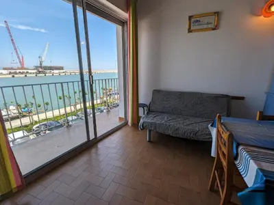 a room with a balcony with a couch and a view of the ocean at T2 Mezzanine à 250m de la plage pour 4/5 pers avec Parking et TV - FR-1-797-31 in Port-la-Nouvelle