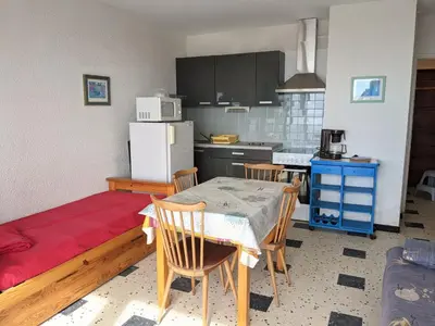 a kitchen with a table and chairs and a refrigerator at Port-la-Nouvelle : Studio front de mer, 4 pers, parking inclus - FR-1-797-32 in Port-la-Nouvelle