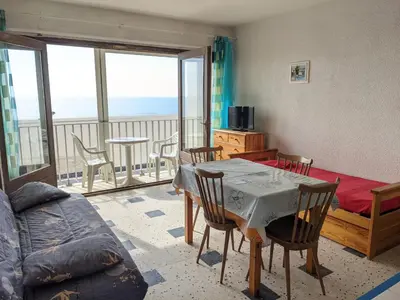 a living room with a table and chairs and a balcony at Port-la-Nouvelle : Studio front de mer, 4 pers, parking inclus - FR-1-797-32 in Port-la-Nouvelle