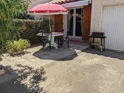 a patio with a table and chairs and an umbrella at Belle Villa T3 Mezzanine, à 450m Plage, 5 Pers, Terrasse, Jardin, Garage & Parking - FR-1-797-33 in Port-la-Nouvelle