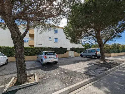 two cars parked in a parking lot in front of a building at Charmant T2 proche plage à Port-la-Nouvelle, terrasse et parking inclus - FR-1-797-29 in Port-la-Nouvelle