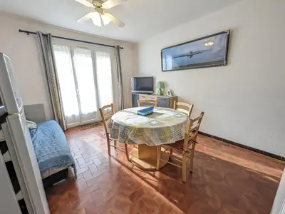 a dining room with a table and chairs and a television at Charmant T2 proche plage à Port-la-Nouvelle, terrasse et parking inclus - FR-1-797-29 in Port-la-Nouvelle