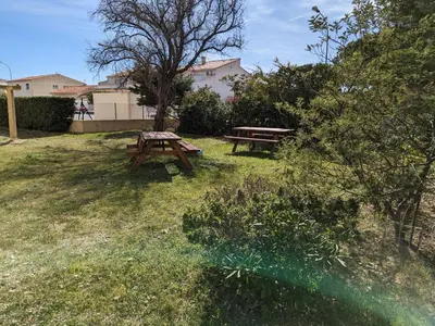 a picnic table and bench in a yard at Charmant T2 proche plage à Port-la-Nouvelle, terrasse et parking inclus - FR-1-797-29 in Port-la-Nouvelle