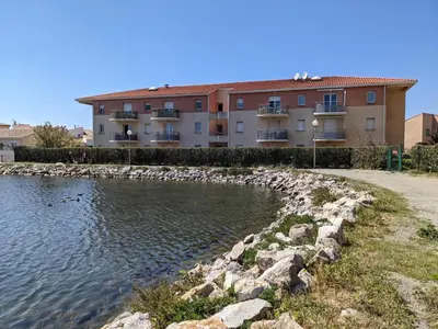 a building with a pond in front of a building at T3 Climatisé RDC avec Terrasse, Parking, Proche Activités - Port-la-Nouvelle - FR-1-797-30 in Port-la-Nouvelle