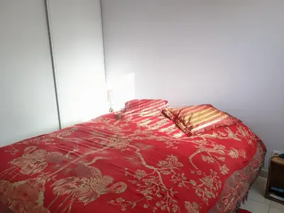 a bed with a red comforter and two pillows at T3 Climatisé RDC avec Terrasse, Parking, Proche Activités - Port-la-Nouvelle - FR-1-797-30 in Port-la-Nouvelle