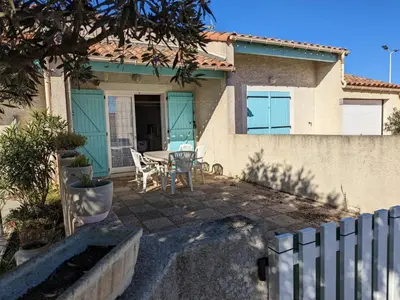 a house with a table and chairs in front of it at Villa T2 Mezzanine Climatisée avec Cour - 6 Pers - Parking - Proche Plage - Meublé Tourisme 1* - FR-1-797-44 in Port-la-Nouvelle