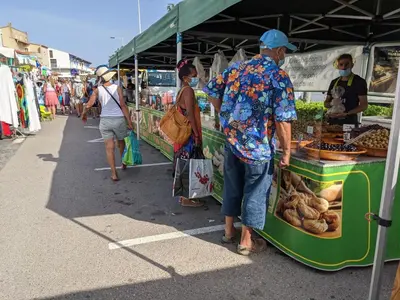 a man standing in front of a food stand at a market at Villa T2 Mezzanine Climatisée avec Cour - 6 Pers - Parking - Proche Plage - Meublé Tourisme 1* - FR-1-797-44 in Port-la-Nouvelle