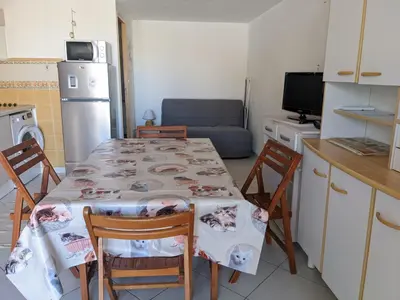 a kitchen with a table and chairs and a kitchen with a refrigerator at Villa T2 Mezzanine Climatisée avec Cour - 6 Pers - Parking - Proche Plage - Meublé Tourisme 1* - FR-1-797-44 in Port-la-Nouvelle