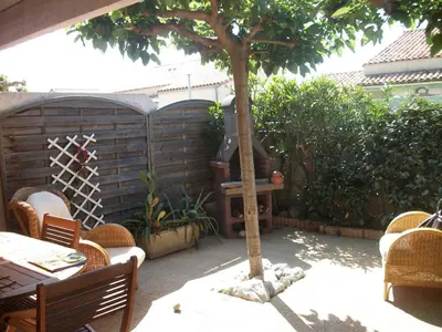 a patio with a tree and a table and chairs at Belle villa climatisée T3 avec mezzanine, jardin arboré, garage et à 900m de la plage, 6/7 personnes - FR-1-797-36 in Port-la-Nouvelle