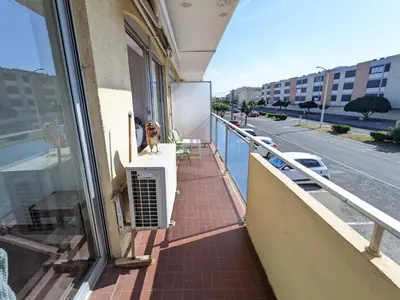 a dog sitting on a window sill on a balcony at T3 spacieux climatisé - 5 pers - près plage, centre & animations - Parking privé - FR-1-797-22 in Port-la-Nouvelle