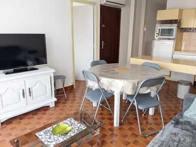 a living room with a table and chairs and a television at T3 spacieux climatisé - 5 pers - près plage, centre & animations - Parking privé - FR-1-797-22 in Port-la-Nouvelle