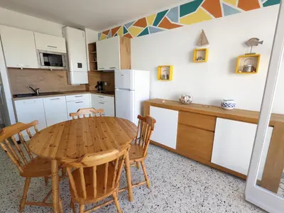 a kitchen with a wooden table and chairs in it at T2 Moderne Port-la-Nouvelle - 4/5p - Parking - Front de Mer - FR-1-797-41 in Port-la-Nouvelle