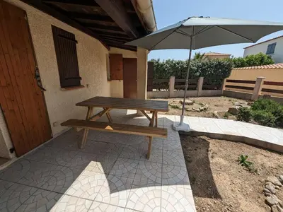 a picnic table with an umbrella on a patio at Maison T2 avec Mezzanine, Cour et Parking – 5 Pers – Proche Plage et Commerces – Bon Prix - FR-1-797-49 in Port-la-Nouvelle