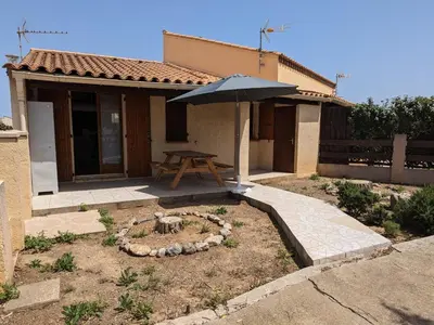 a table with an umbrella in front of a house at Maison T2 avec Mezzanine, Cour et Parking – 5 Pers – Proche Plage et Commerces – Bon Prix - FR-1-797-49 in Port-la-Nouvelle