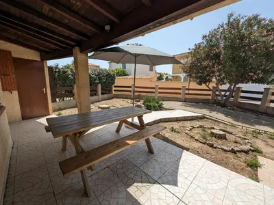 a wooden bench sitting under an umbrella on a patio at Maison T2 avec Mezzanine, Cour et Parking – 5 Pers – Proche Plage et Commerces – Bon Prix - FR-1-797-49 in Port-la-Nouvelle