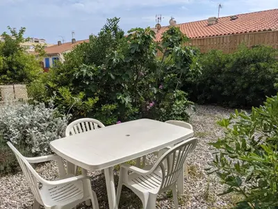 a white table and chairs in a garden at T2 Climatisé, 2 Cours, Proche Plage, Parking Privé, 5 Pers., Animaux Acceptés - FR-1-797-58 in Port-la-Nouvelle