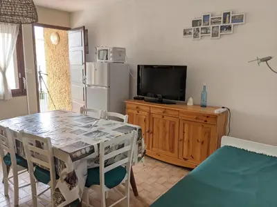 a dining room with a table and a tv at Villa T2 climatisée, 5 pers, proche plage, cour, jardin, barbecue, parking, 2* Meublés Tourisme - FR-1-797-57 in Port-la-Nouvelle