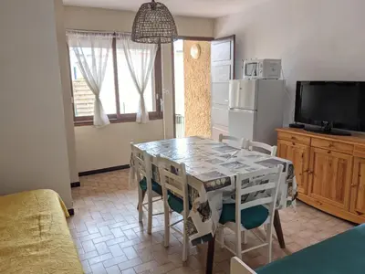 a kitchen with a table and chairs and a refrigerator at Villa T2 climatisée, 5 pers, proche plage, cour, jardin, barbecue, parking, 2* Meublés Tourisme - FR-1-797-57 in Port-la-Nouvelle
