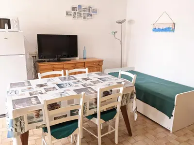 a kitchen with a table with chairs and a television at Villa T2 climatisée, 5 pers, proche plage, cour, jardin, barbecue, parking, 2* Meublés Tourisme - FR-1-797-57 in Port-la-Nouvelle