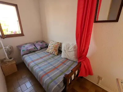 a small bed in a room with a red curtain at Villa T3 Mezzanine Climatisée, Proche Plage, Parking et Terrasse - 6 Pers - FR-1-797-56 in Port-la-Nouvelle