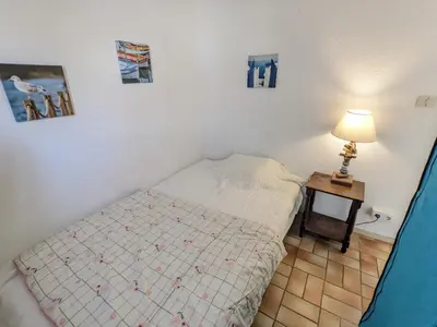 a small bedroom with a bed and a table with a lamp at Villa T3 Mezzanine Climatisée, Proche Plage, Parking et Terrasse - 6 Pers - FR-1-797-56 in Port-la-Nouvelle