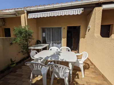 a patio with white tables and chairs on a house at Villa T3 Mezzanine Climatisée, Proche Plage, Parking et Terrasse - 6 Pers - FR-1-797-56 in Port-la-Nouvelle
